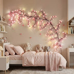 Pink cherry blossom branch lights arranged above a bed