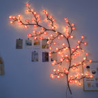 Cherry blossom branch lighting along a bedroom wall