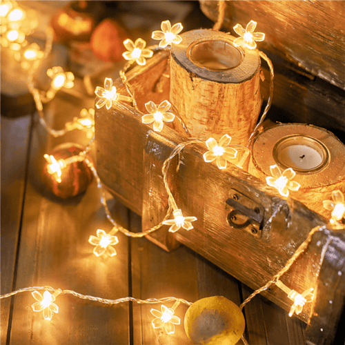 Cherry blossom fairy lights draped over rustic wood and candles.