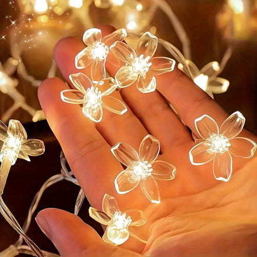 Cherry blossom string lights showing clear flower covers against a hand.