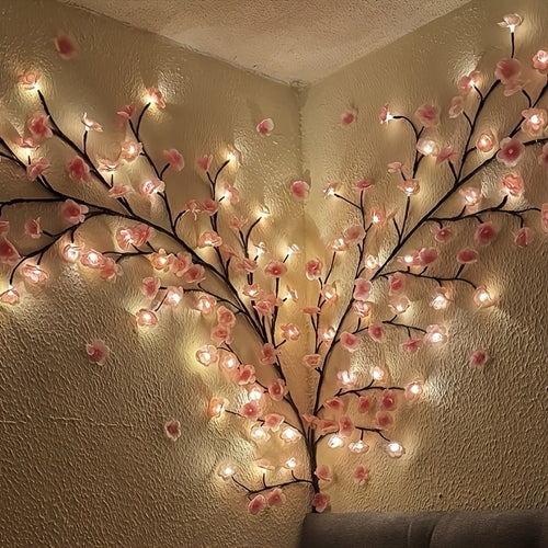 Pink cherry blossom vine lights arranged along a wall