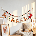 Christmas felt garland set with reindeer, Santa sleigh and pom poms on a pale wall.
