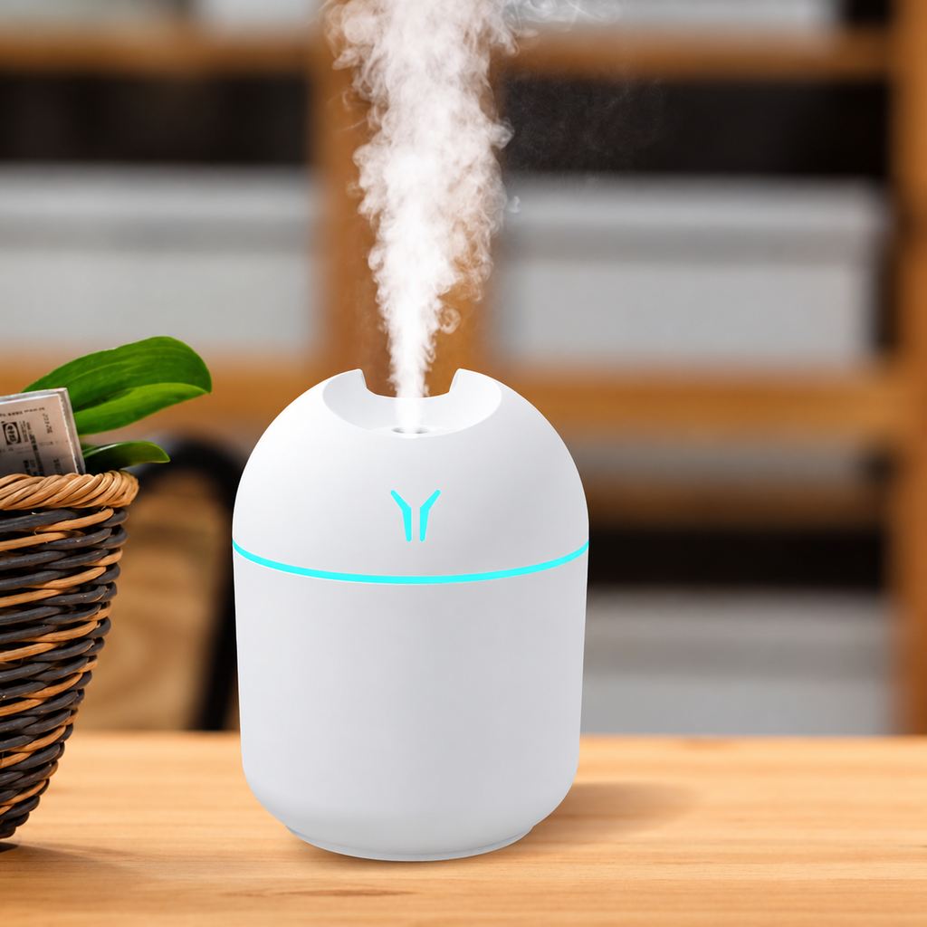 White humidifier with aqua lighting releasing mist on a wooden tabletop beside a plant