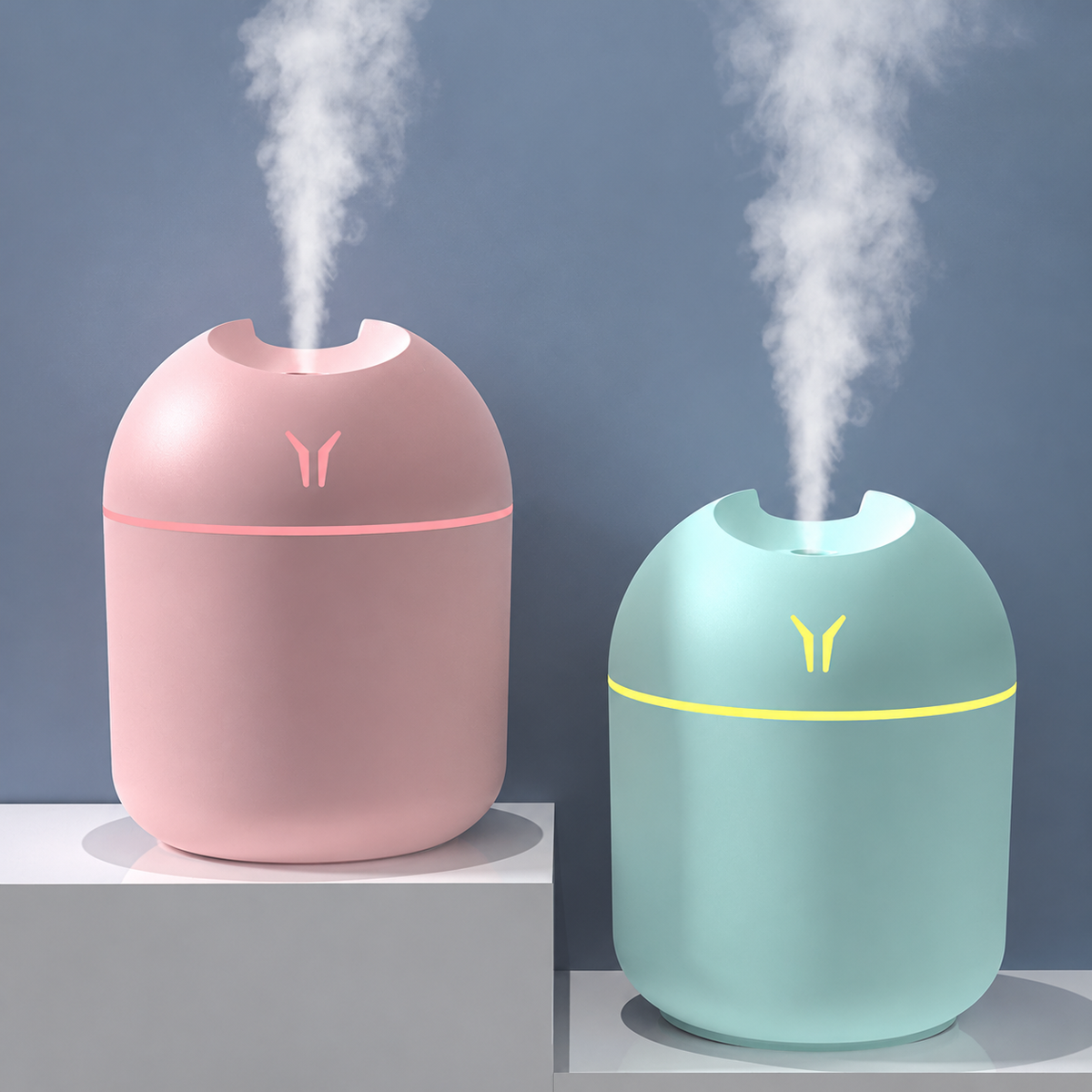 Pink and blue humidifiers releasing mist on grey stepped stands