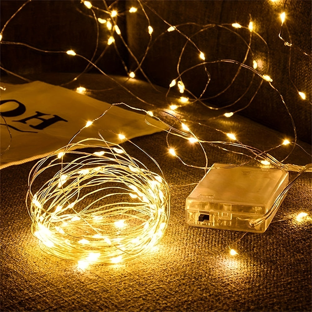 Copper fairy lights glow beside their battery box on a textured surface.