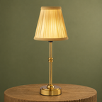 Gold cordless table lamp with silk-look shade on oak against a muted sage backdrop