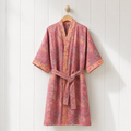 Pink cotton robe with a vintage floral print hangs against a bright paneled background.