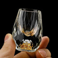 Faceted crystal drinking glass with a rounded profile and gold fleck detail at the base