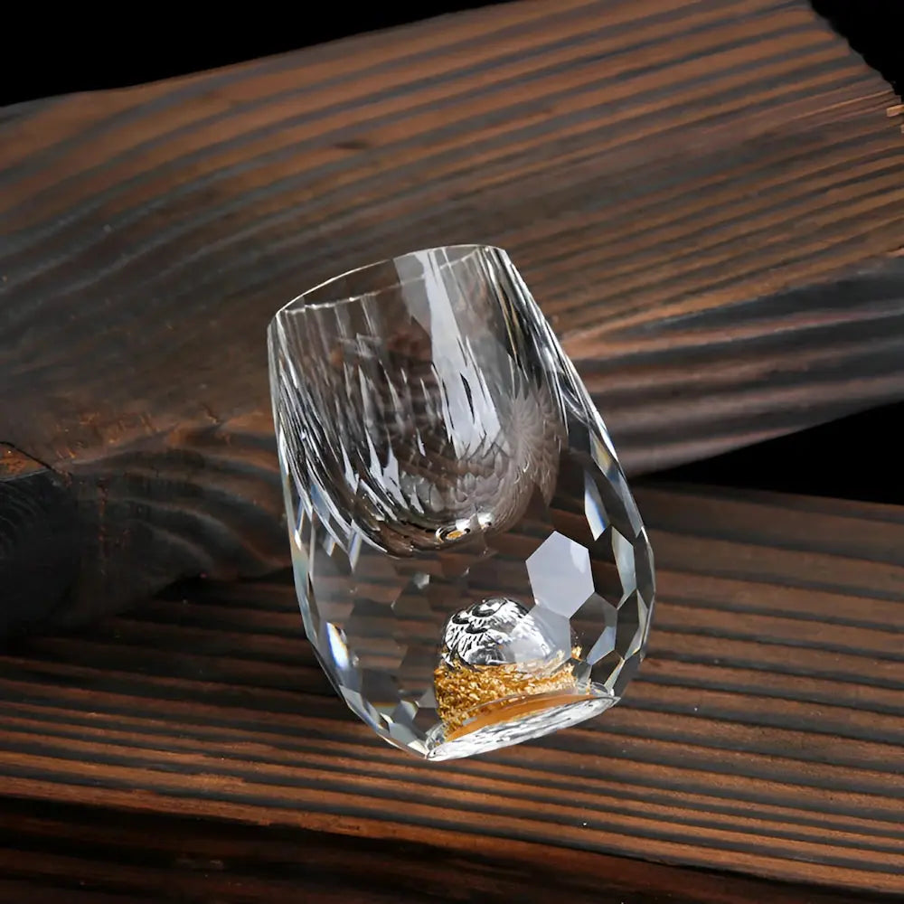 Faceted crystal drinking glass with a rounded profile and gold fleck detail at the base