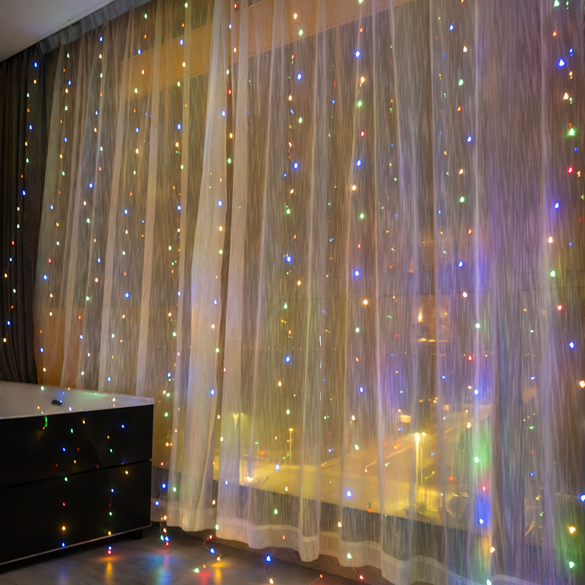 Multicolor curtain fairy lights glowing across sheer window curtains.