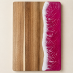 Pink resin cutting board shown from above on a warm cream studio background.