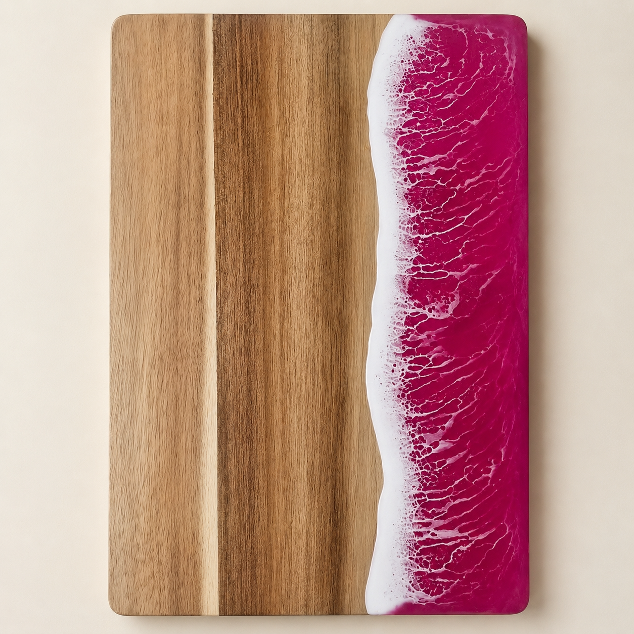 Pink resin cutting board shown from above on a warm cream studio background.