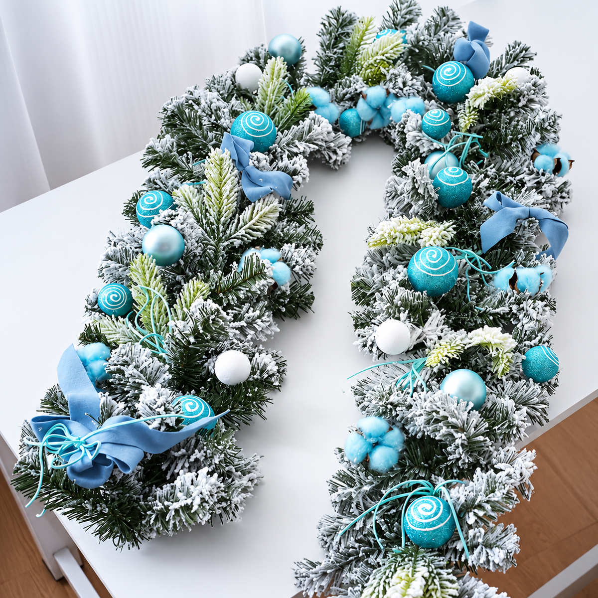 Blue decorated Christmas garland with snowy greenery baubles and ribbon details on a table