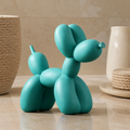 Balloon dog sculpture in glossy teal resin on a neutral stone console