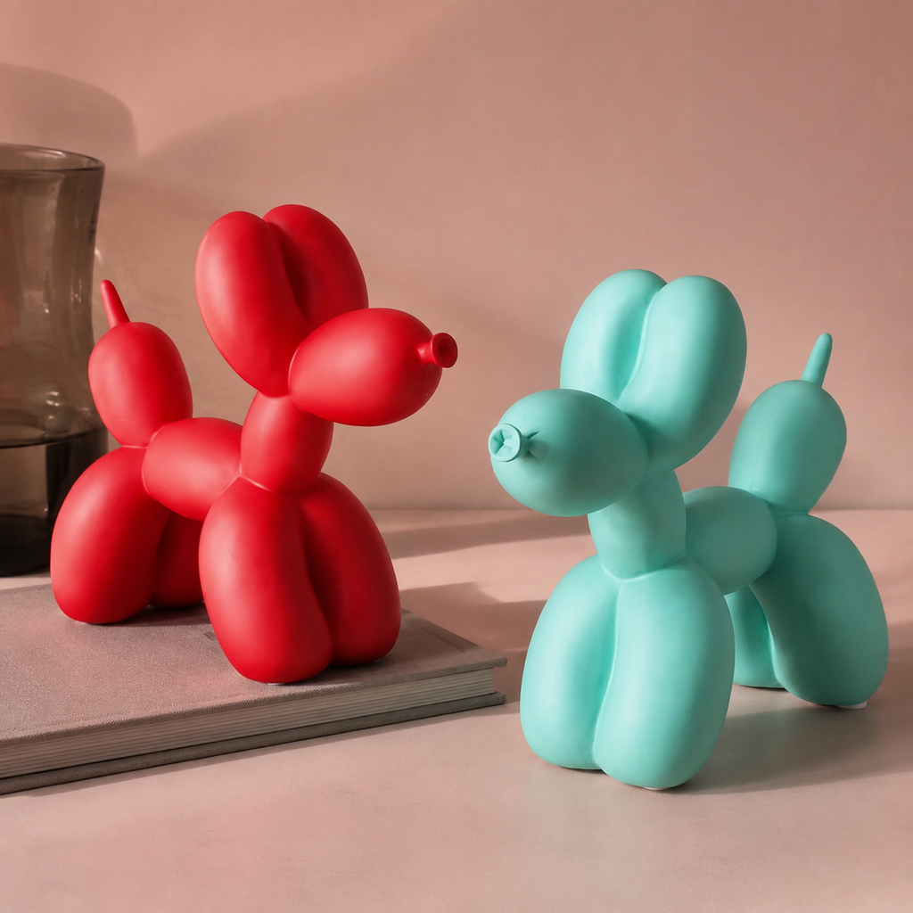 Balloon dog sculpture pair in red and teal on a blush stone tabletop