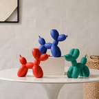 Balloon dog sculpture trio in red, blue and teal on a pale stone shelf