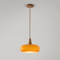 Orange pendant light with a rounded shade and wood-look stem hanging against a neutral background.