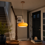 Orange pendant light glowing above a table in a dark dining room with built-in shelving.