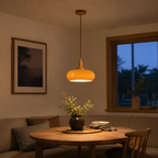 Orange pendant light glowing over a dining table in a softly lit evening room.