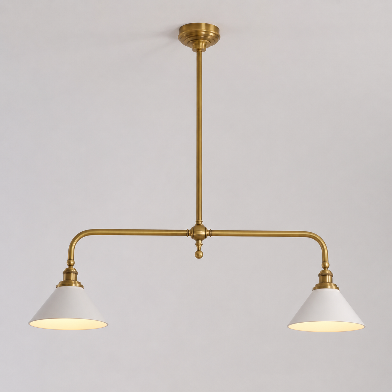 Brass two head pendant light with white cone shades displayed against a plain neutral background.