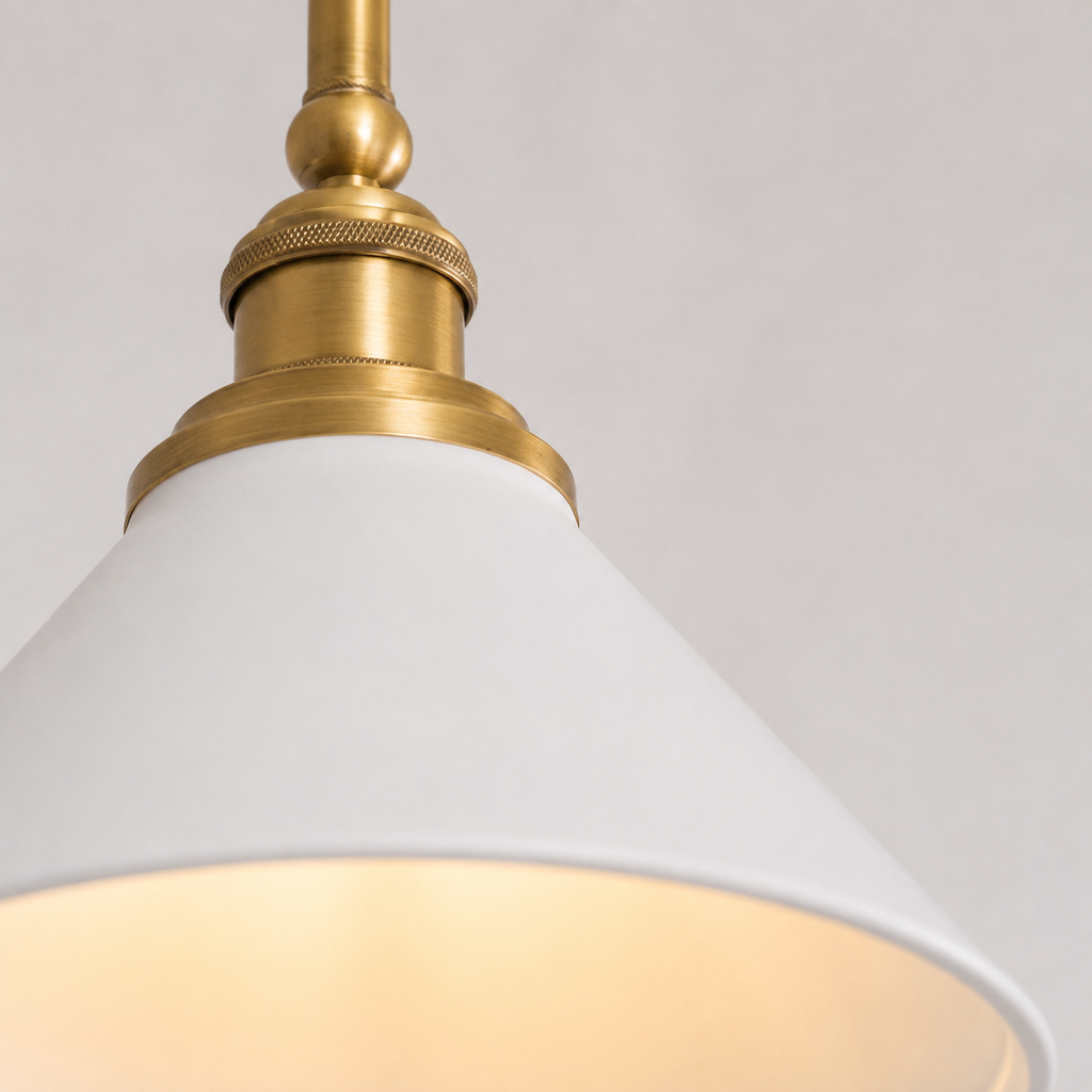 Close-up of a pendant light with a brass fitting and smooth white cone shade.