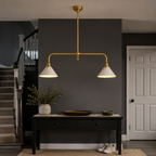 Brass two head pendant light illuminating a dark console table in a modern interior.