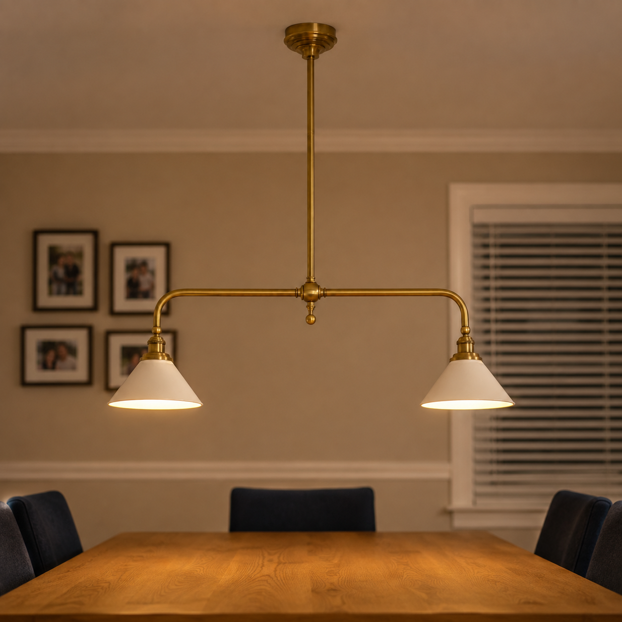 Brass two head pendant light hanging above a wooden dining table with black chairs.