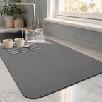 Dish drying mat in gray holding cups and glasses beneath soft window light