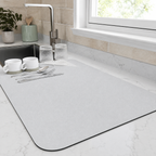 Dish drying mat in white holding cups and glasses beside a bright kitchen window