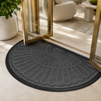 Dark gray semi-circular sunburst door mat at a brass-framed glass entry.