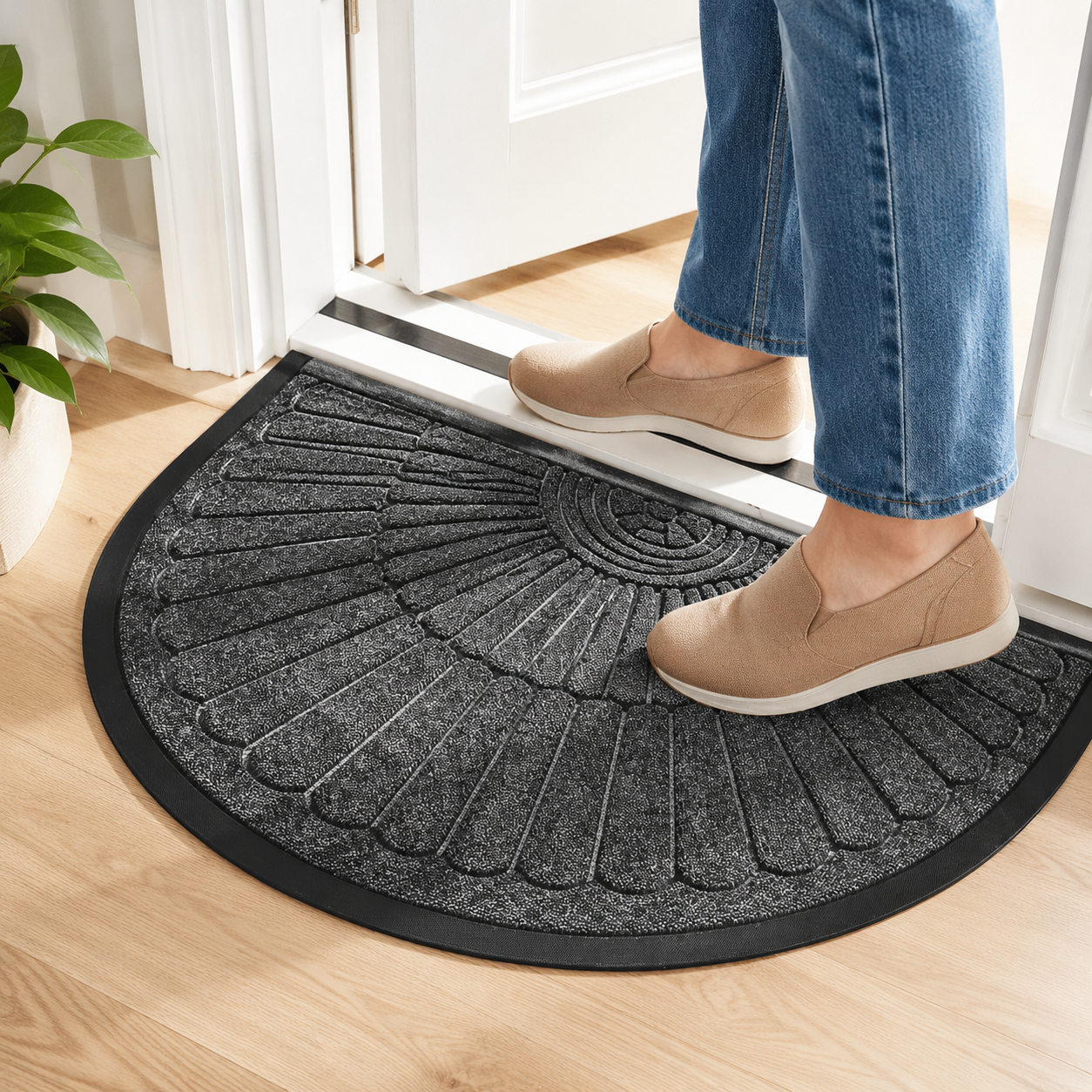 Person stepping onto the dark gray semi-circular door mat at a bright home entry.