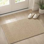 Beige door mat lies inside a doorway beside slippers on light wood flooring.