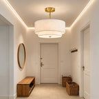 Gold drum ceiling light with a layered linen shade above an entryway.