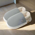 Light gray electric heated slippers on a wooden floor