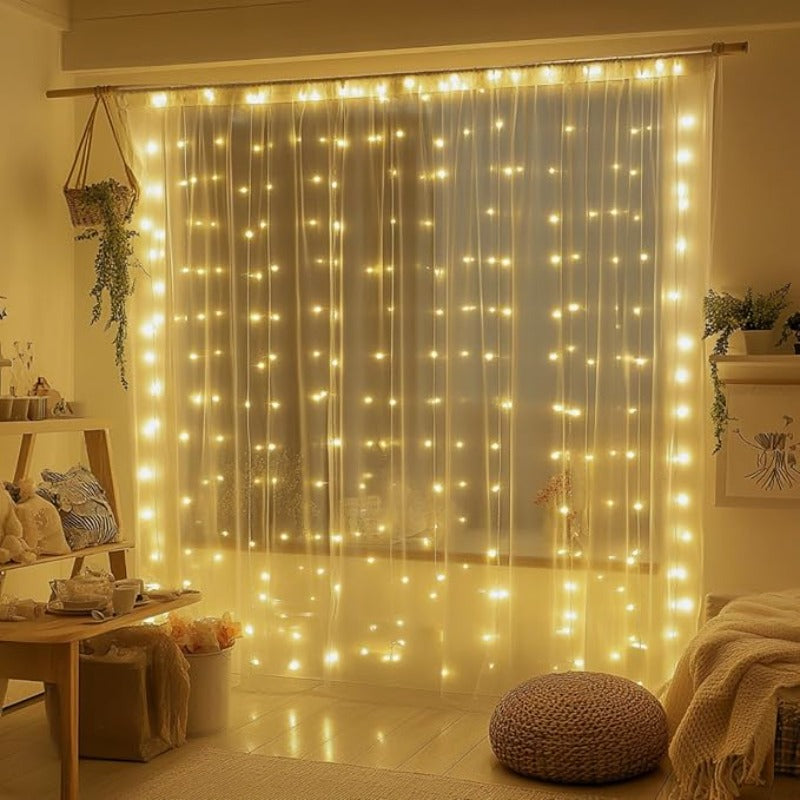 Fairy curtain lights hanging across a bedroom window above a floor cushion.
