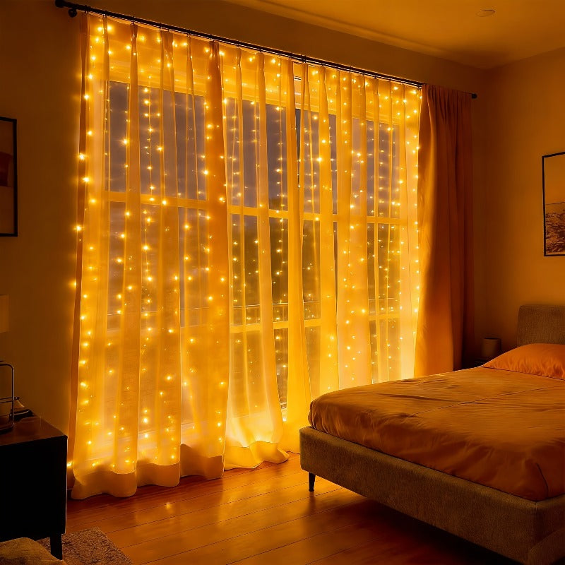 Fairy curtain lights covering a bedroom window behind sheer white curtains.