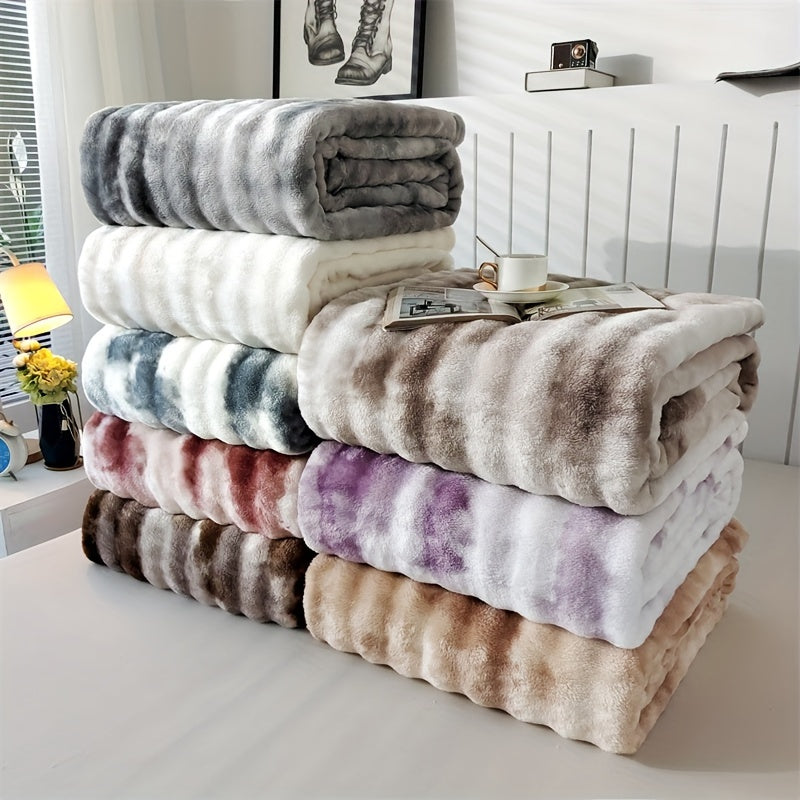 Faux fur throw blankets in several marbled colors stacked beside a bed.