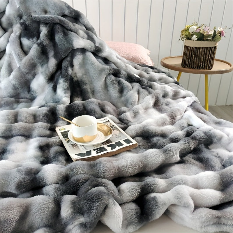 Gray faux fur throw blanket with a cup and tray resting on its raised surface.