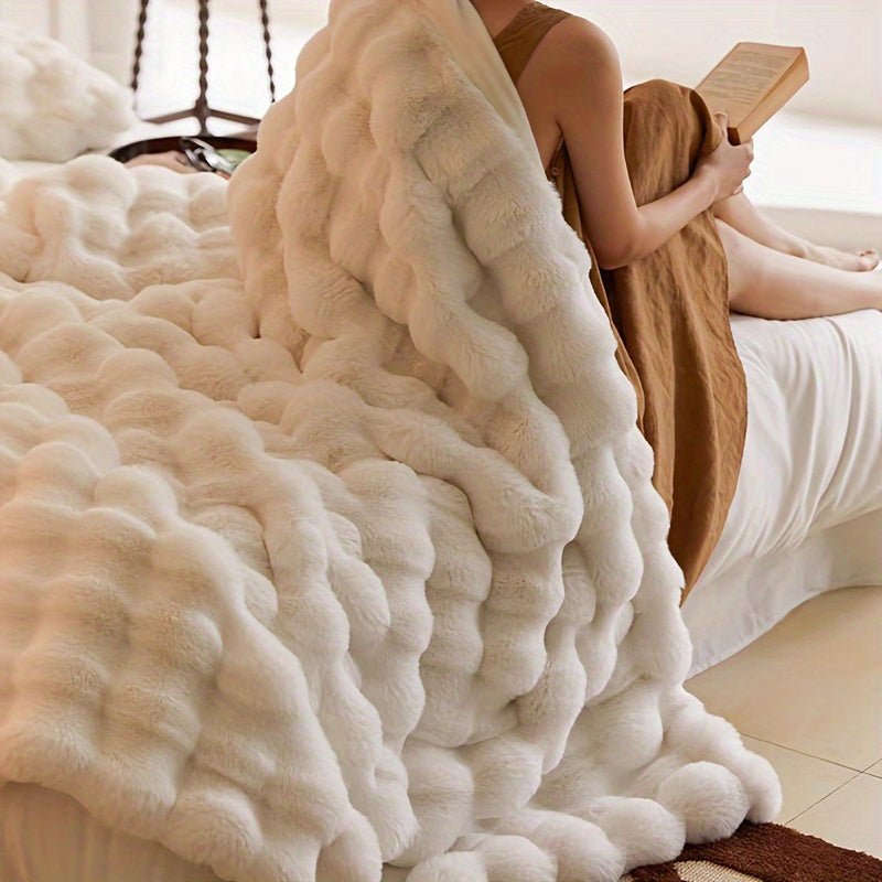 A person reading with a cream faux fur throw blanket over their shoulders.