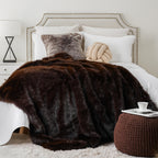 Dark brown faux fur throw blanket spread across a white bed.