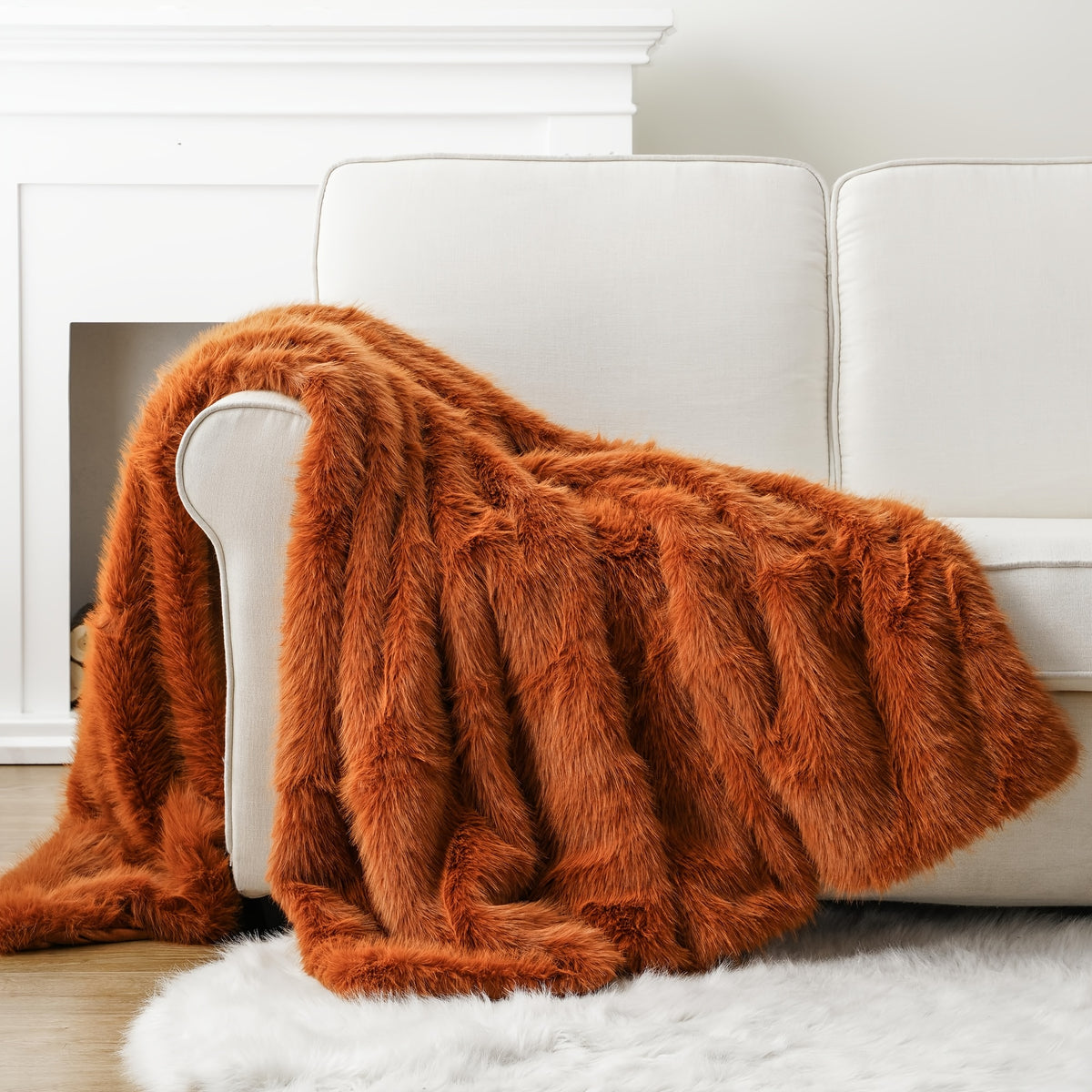 Orange faux fur throw blanket draped over a white couch.