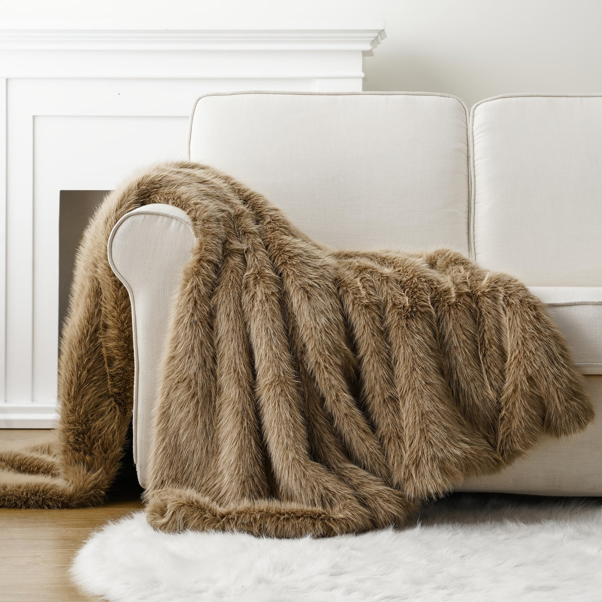 Tan faux fur throw blanket draped over the arm of a white couch.