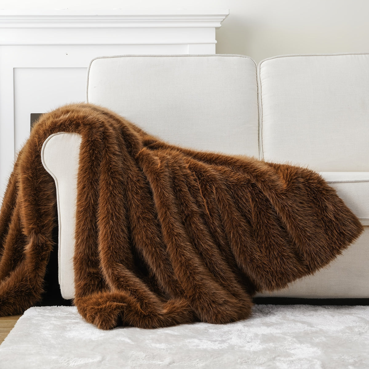 Brown faux fur throw blanket draped over a white couch.