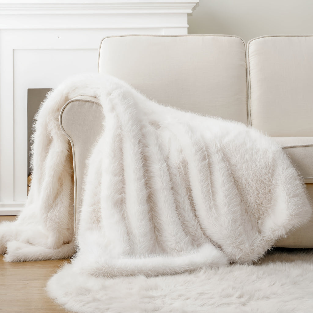 White faux fur throw blanket draped over a white couch.