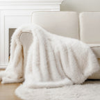 White faux fur throw blanket draped over a white couch.