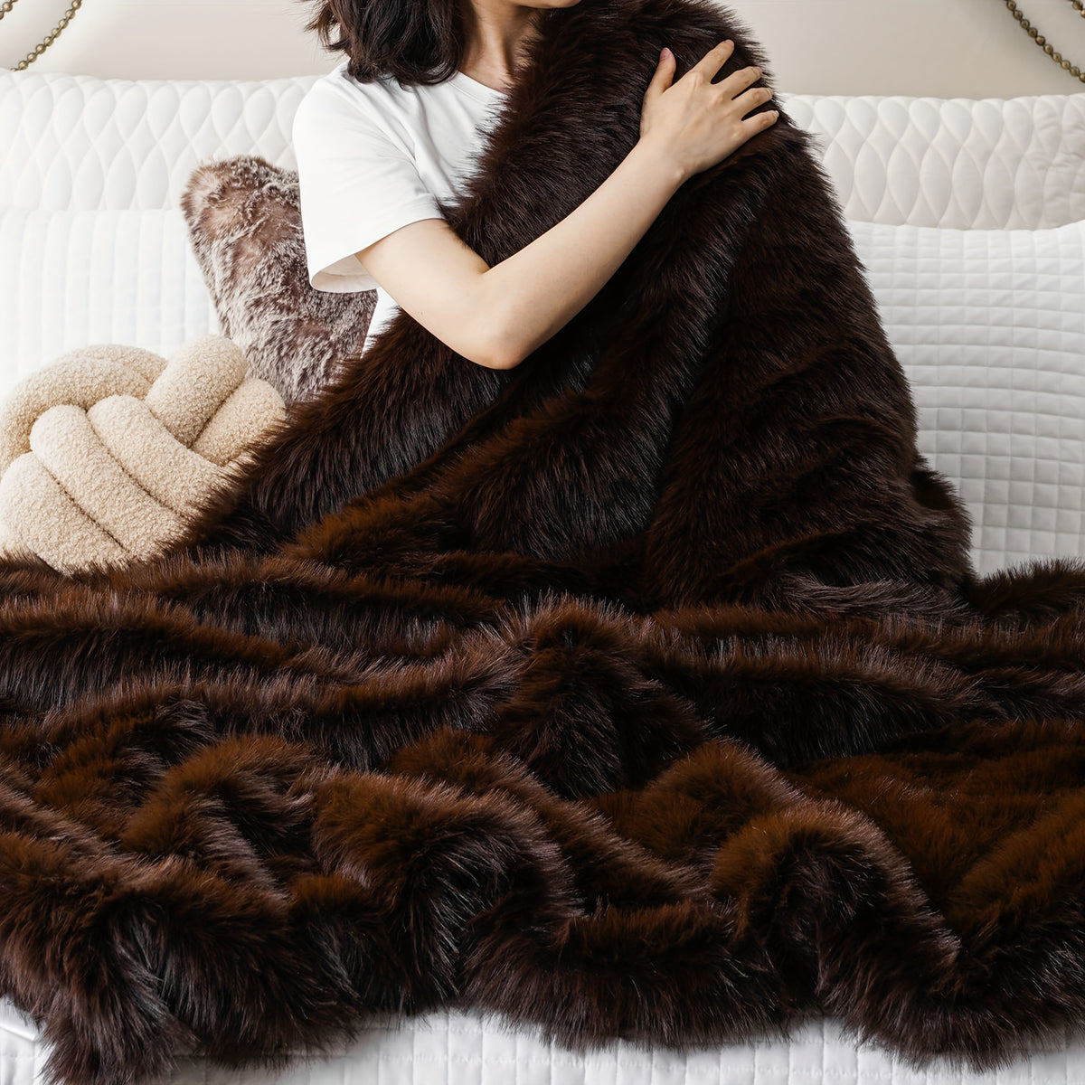 A person wrapped in a dark brown faux fur throw blanket.