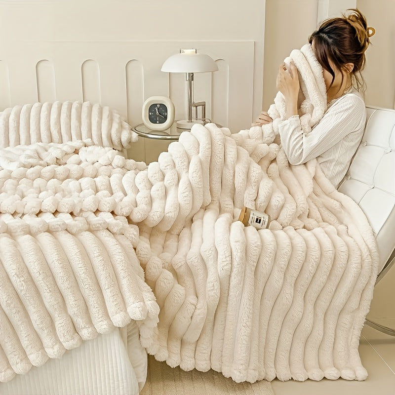A woman sitting with a white faux fur throw blanket on a cream couch.