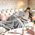 Gray faux fur throw blanket draped over a seated woman using a laptop