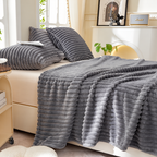Gray faux fur throw blanket spread across a bed with matching decorative cushions