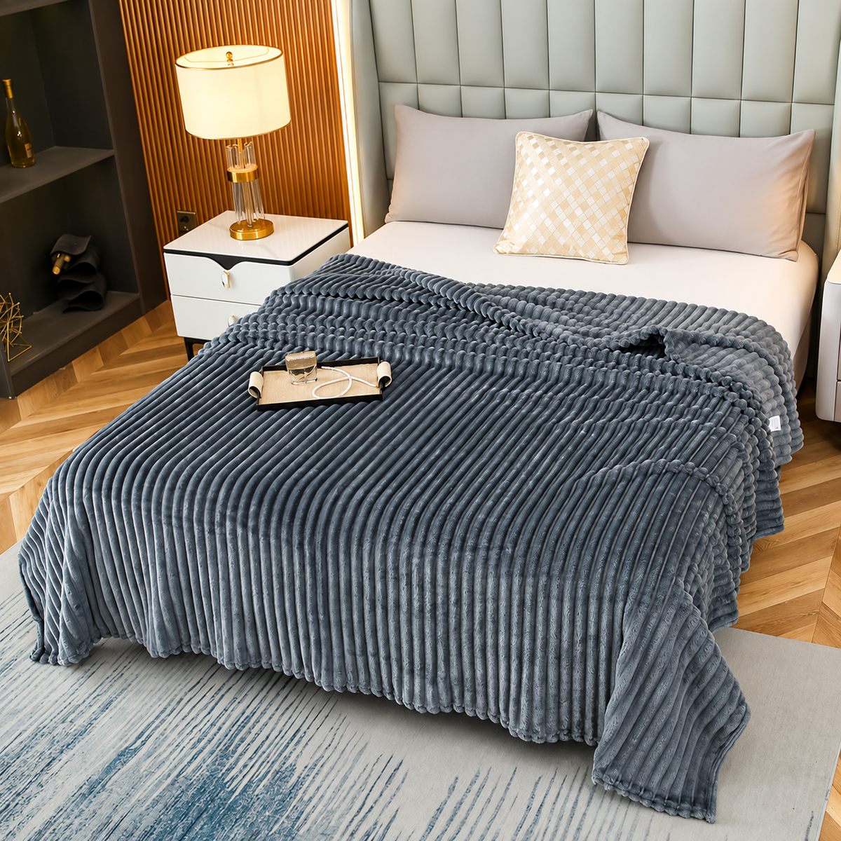 Dark gray faux fur throw blanket with raised stripes spread across a bed